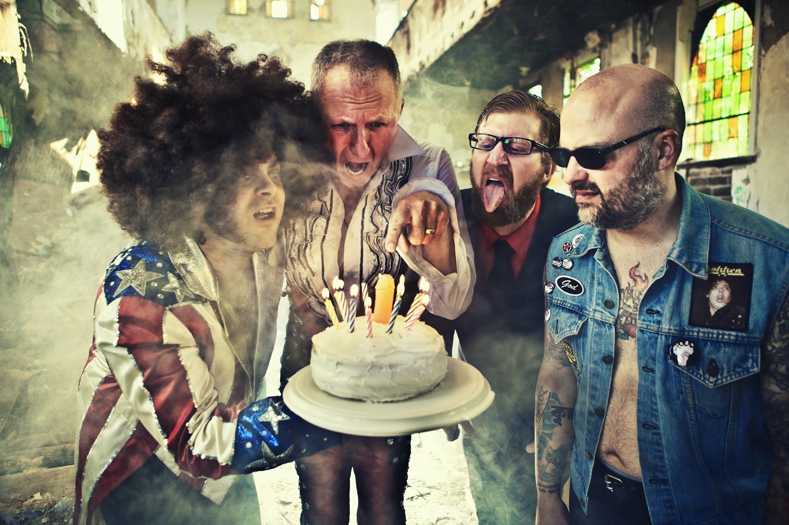Bandmembers of The Meatmen staring and pointing at a cake with candles.
