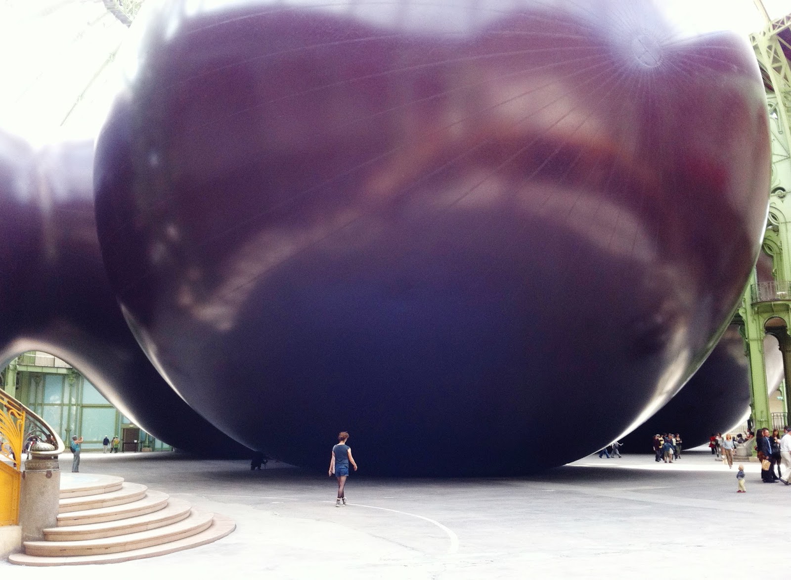 A spectator stands in front of a massive spherical sculpture, over 30m in height. 