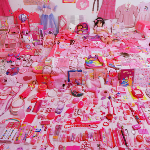 A child laying on a floor filled with pink merchandise. 
