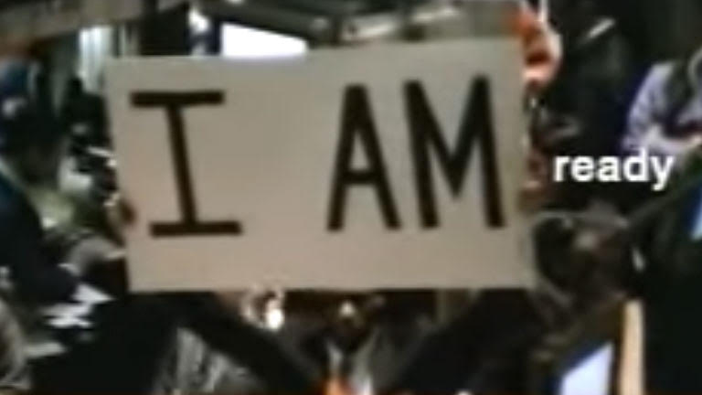 Protestor holds a sign saying "I am" with the word "ready" is pasted overtop the image in postproduction. 