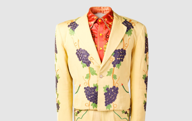 A rich, glossy red undershirt beneath a dusty, pale yellow rhinestone jacket and pants. Grape vines sewn onto the jacket descend from the shoulders down to the pants.
