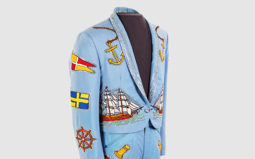 A sky blue rhinestone suit jacket and pants with nautical-themed patches sewn on.