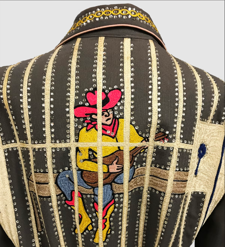 A black rhinestone jacket. Vertical and lines going up and down the entire back form bars on a jail cell beyond which a lonely cowboy plays a guitar.