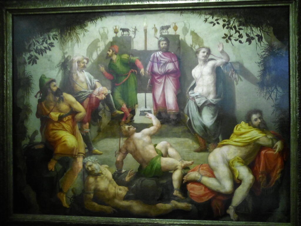 A photograph of a 16th century oil painting depicting eight men in chains. Behind them is a wall that has with various shadows projected onto it.