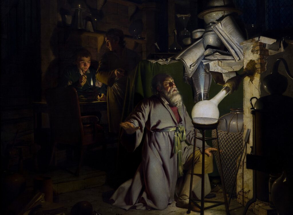 An old, white-bearded man kneels on the floor of a messy and dark laboratory, lit only by a bright point of light emerging from the side of a glass flask. Two young boys look on as the man stares at the small plume of light in awe.